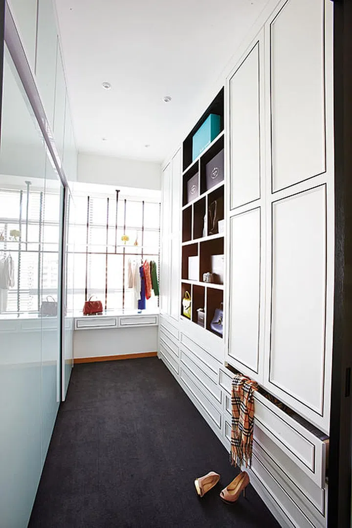 The husband's side of the wardrobe features two large panels of opaque glass mounted on a thin steel frame, while the wife's side has doors inset with wood moulding.