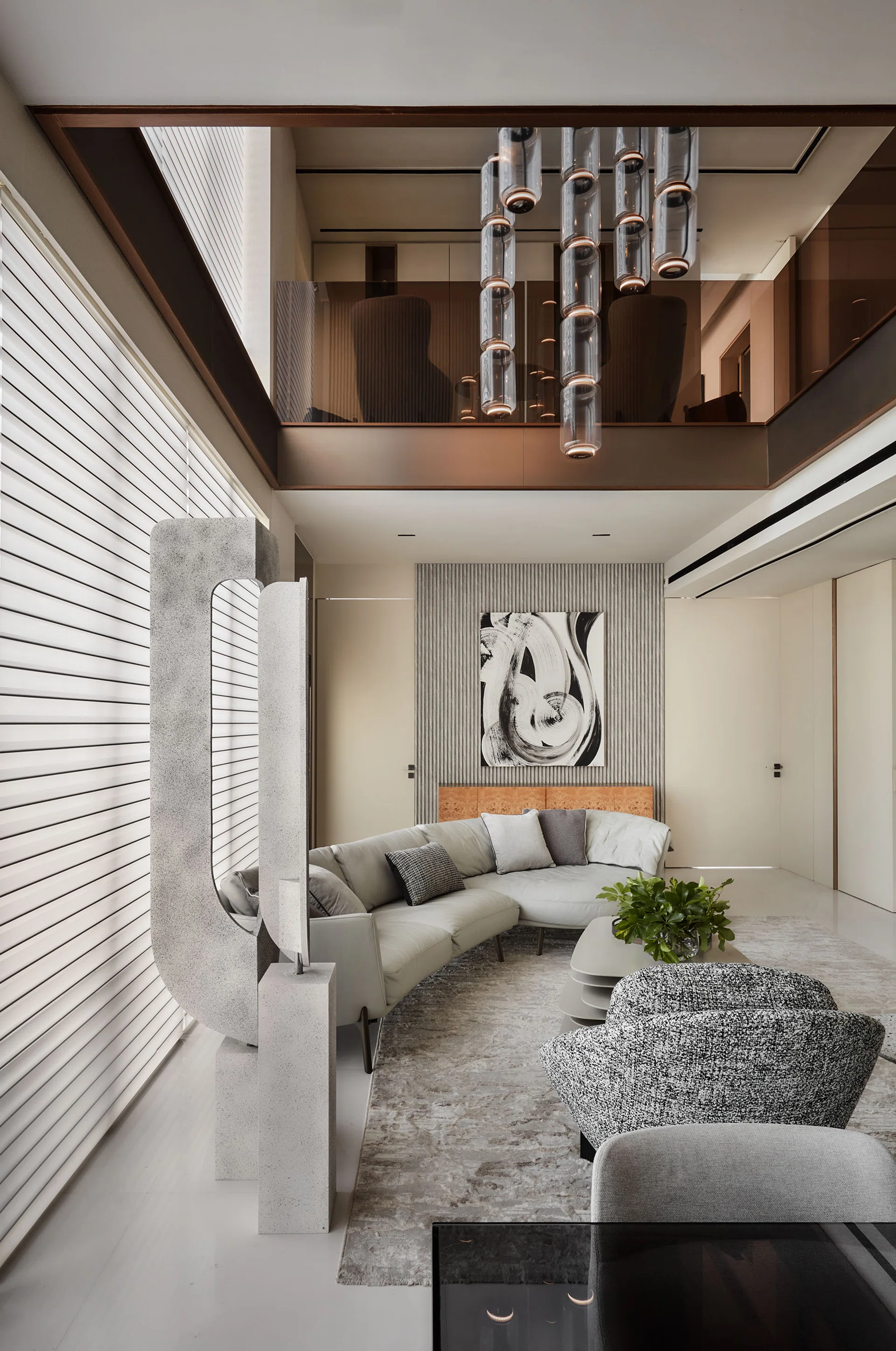 The vertically elongated form of the custom designed sculpture in one corner of the living room complements the double volume space.
