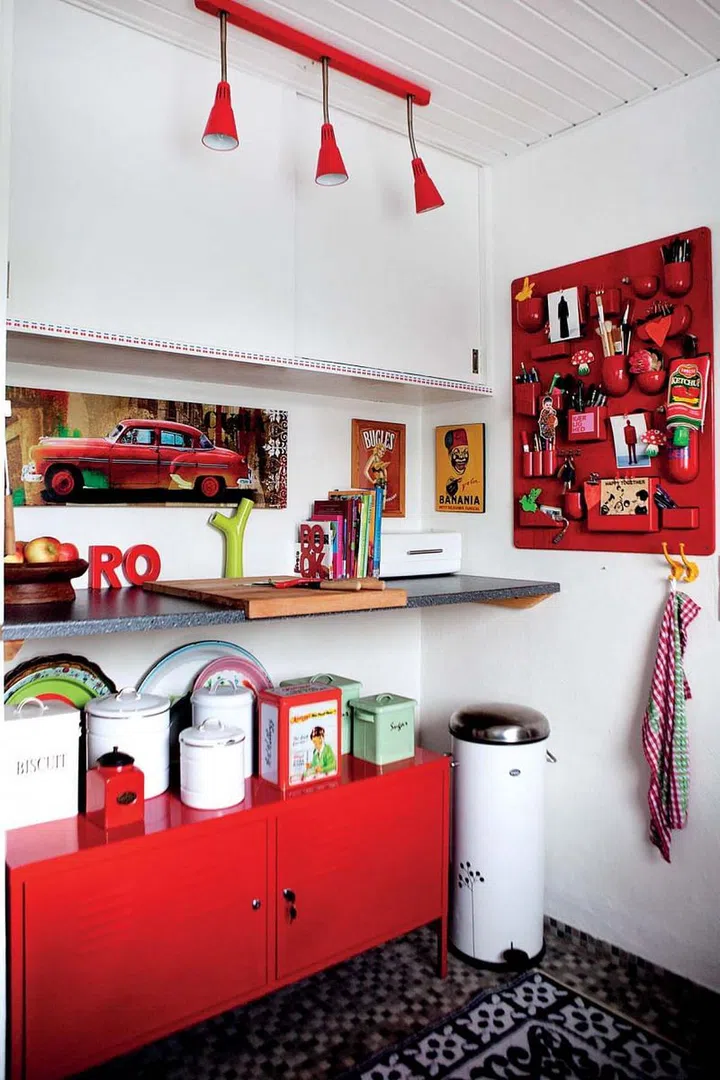 The fire engine red leads the way in this corner of the kitchen. The metal cabinet from Ikea and a wall-mounted storage and display board make funky yet functional statements.