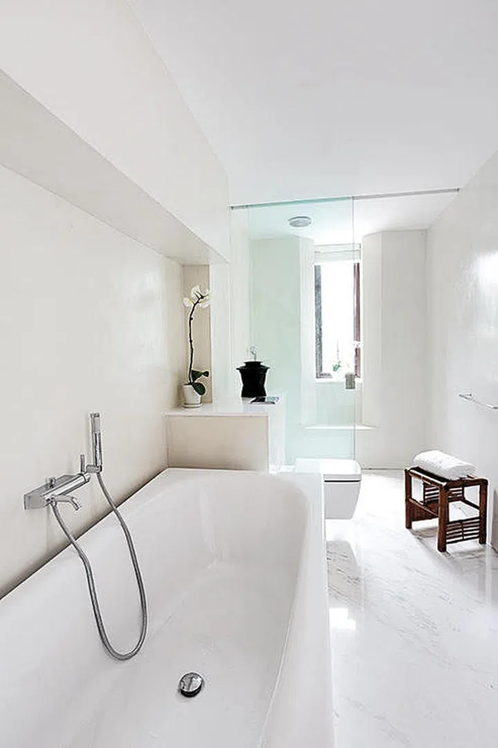 A touch of wood warms up the all-white master bathroom, which was made more spacious by removing the wardrobes at one end. Interior design by Spacedge Designs