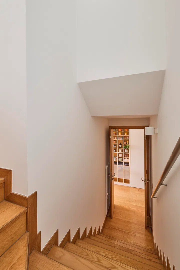 A timber staircase connects the lower and upper levels, offering a simple transition between social and private spaces.