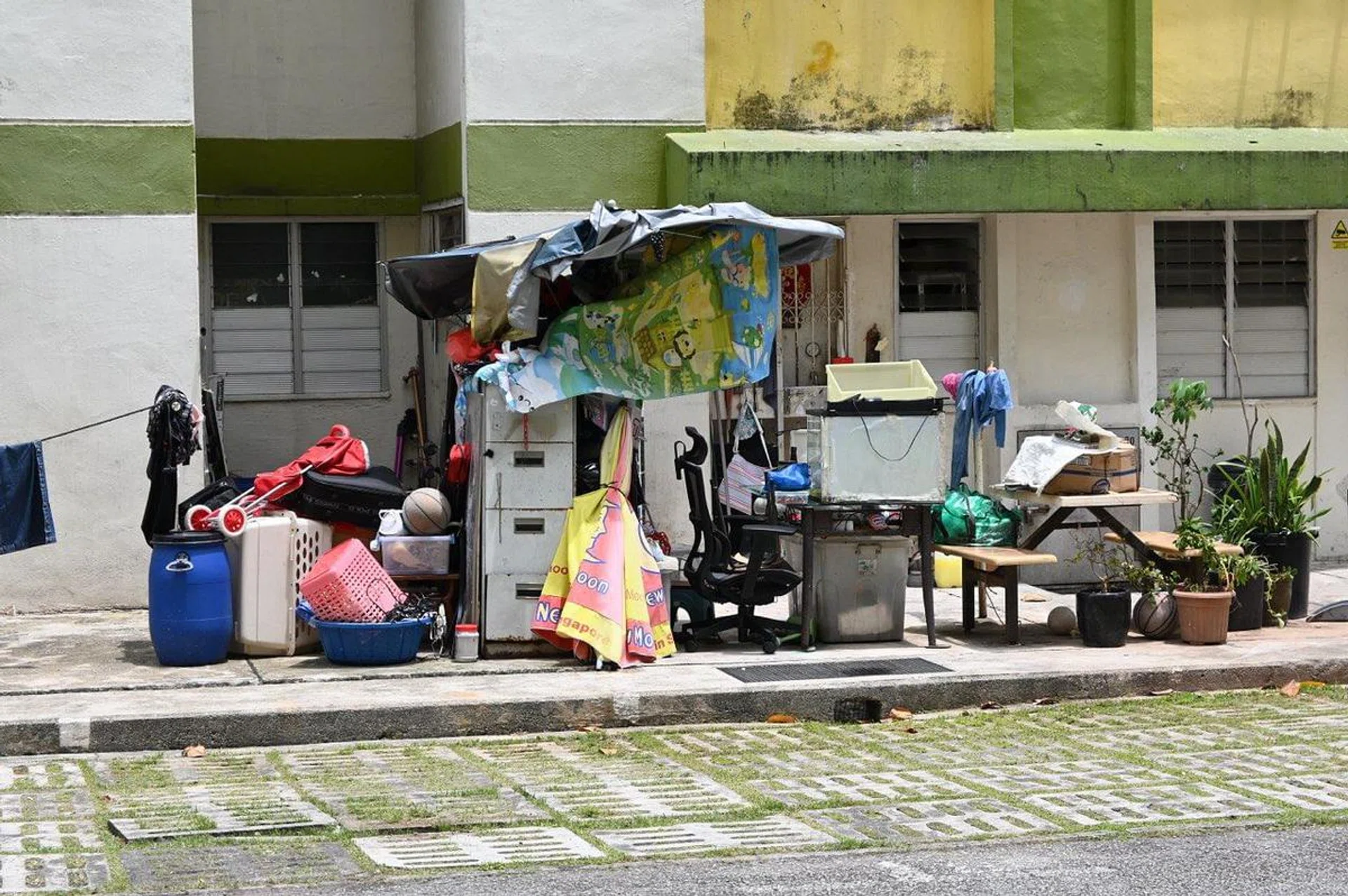 a bunch of rubbish piled up against the side of a HDB