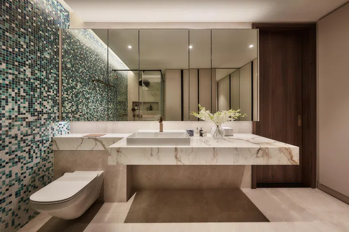 Mirrored cabinetry and a cantilevered marble vanity amplify the sense of openness, balancing the master bathroom’s vibrant mosaic feature wall.