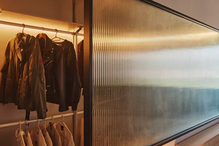 Fluted glass appears throughout the flat, from bedroom partitions to doors and bathrooms, becoming one of the renovation’s defining design features.