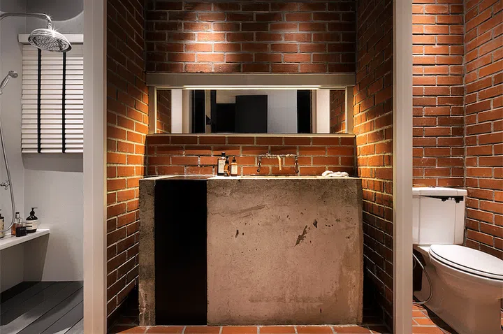 The shower area and water closet are enclosed within smaller cubicles, each flanking a shared vanity area. Interior designby Upstairs.