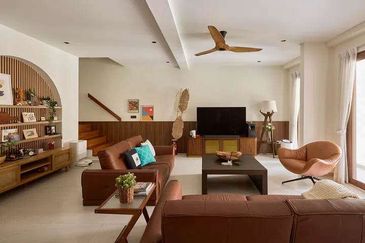 A low, conversational seating arrangement keeps the living room open and relaxed, while the staircase and timber-lined wall recede quietly into the background.