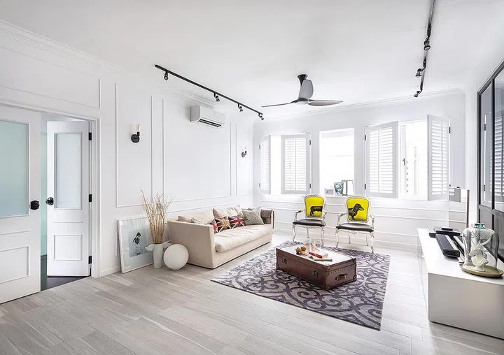 Wainscotting walls for an all-white living room with wooden louvre windows.