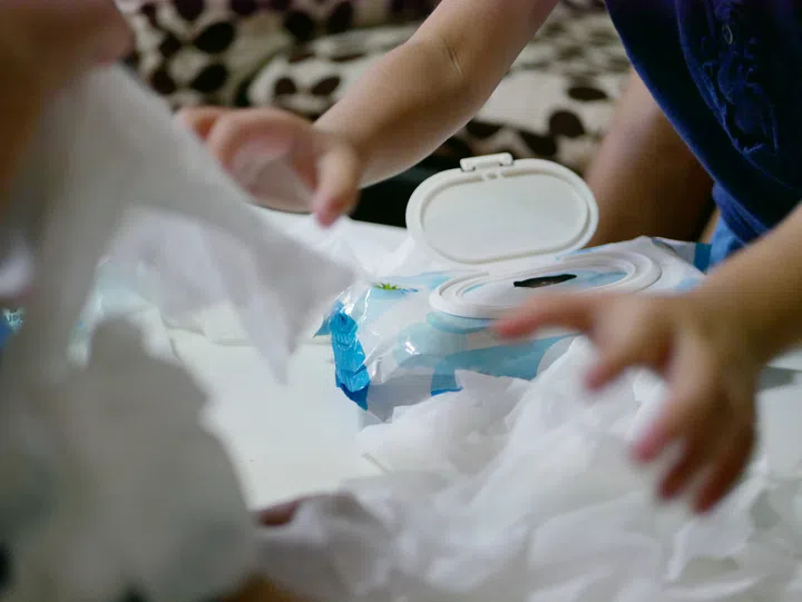 Baby wipes being pulled out from the package all over the table by babies - messy play contributes to development of a child’s physical, cognitive, sensory and creative abilities.