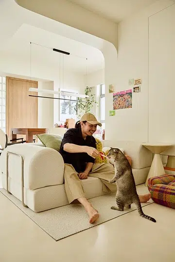 Kai relaxes in the open-plan living area with his cat Monmon.