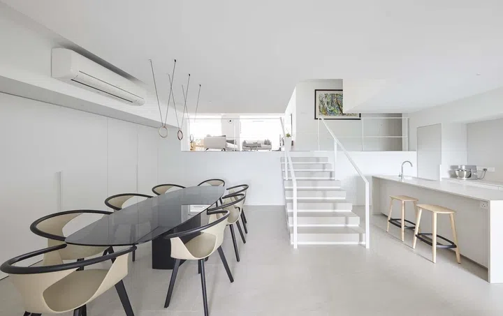 Dining area sits next to the kitchen and kitchen island in this all white 3,500 sq ft 4-bedroom Pandan Valley condo.