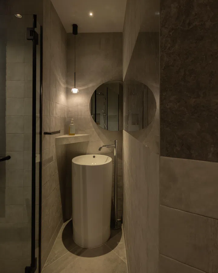A narrow, angular footprint is reworked into a comfortable passage, with a mirrored strip extending the sense of depth.
