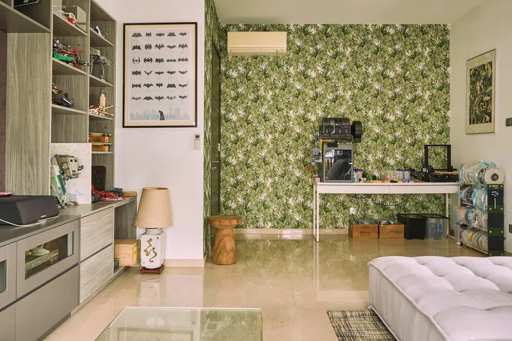 The green, tropical wallpaper is kept to a L-shaped corner by the guest room door.