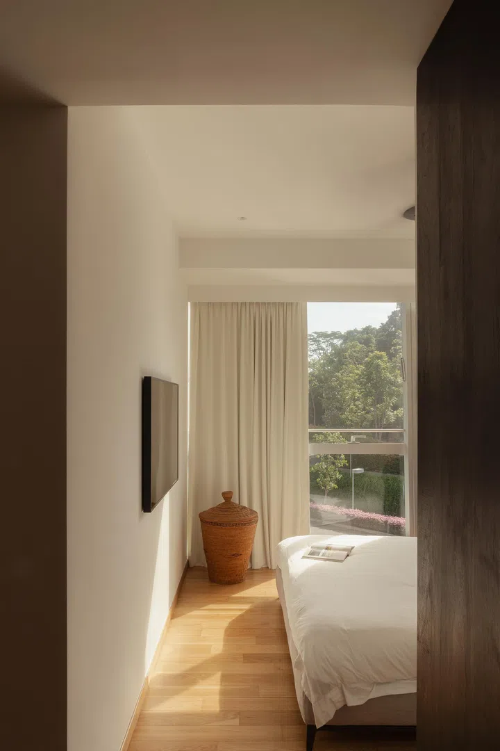 The master bedroom opens to views of greenery, framed by soft drapery and natural light.