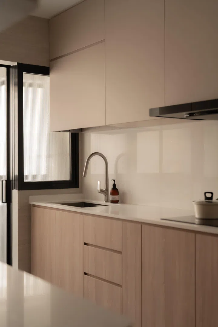 A pared-back galley kitchen balances warm wood cabinetry with light surfaces, allowing function to take centre stage without breaking the home’s cohesive design language.