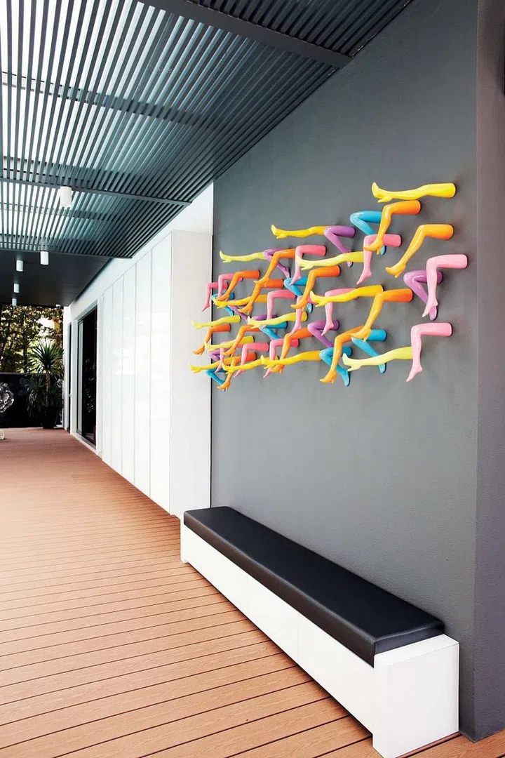 A plain grey wall by the porch is brought to life with a colourful and cheeky art installation made up of many plastic high-heeled legs.  