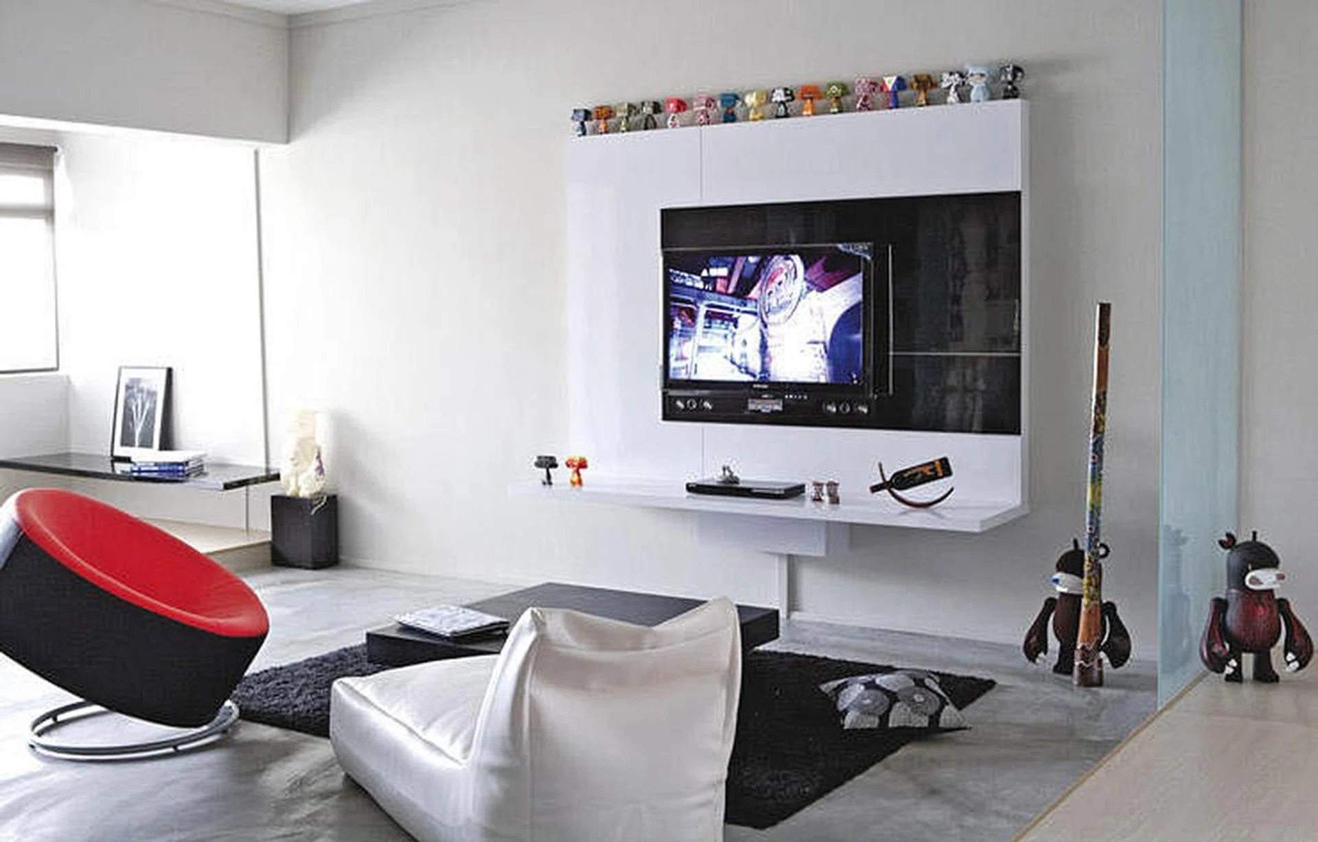 While most TV feature walls are designed to stand out, this one recedes into the white concrete wall, allowing the kooky Mad*l figurines above to steal the spotlight.