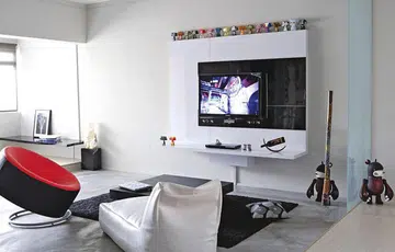 While most TV feature walls are designed to stand out, this one recedes into the white concrete wall, allowing the kooky Mad*l figurines above to steal the spotlight.