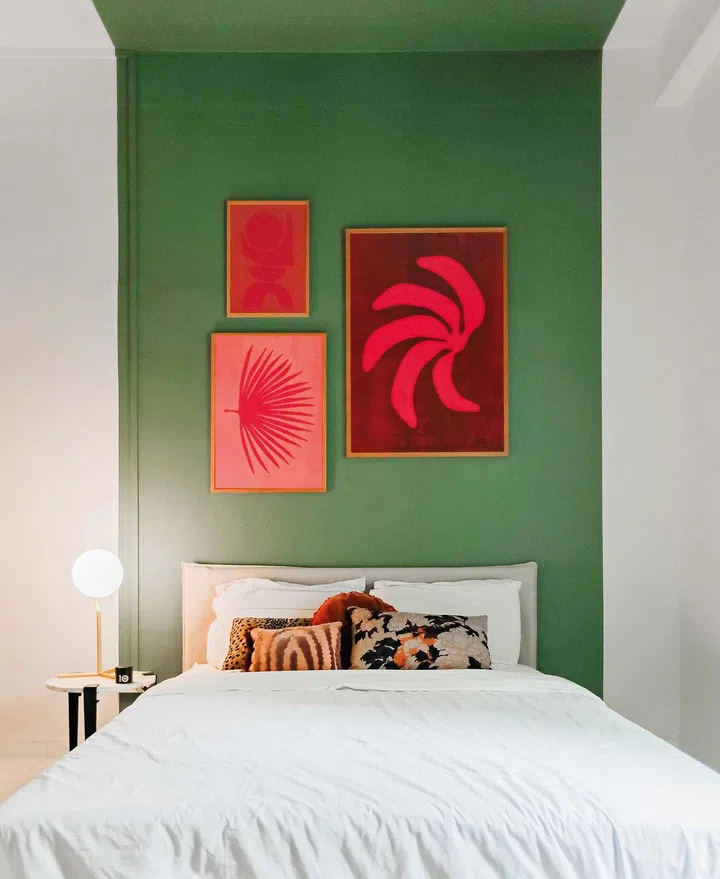 Pink paintings hanging on a green wall, with a bed