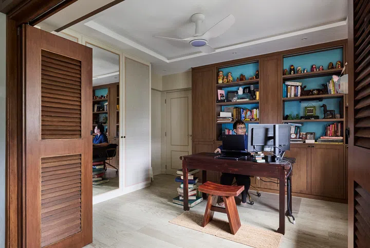 The study, lined with turquoise shelves holding books, old cameras, and treasured gifts. in a 4-room HDB resale in Sunset Way.