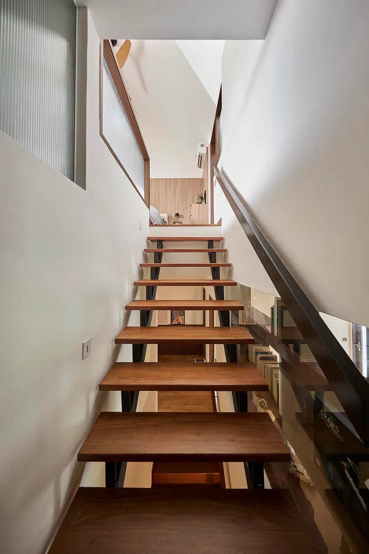 Timber treads and a glass balustrade allow light to filter through the stairwell as it rises to the attic.