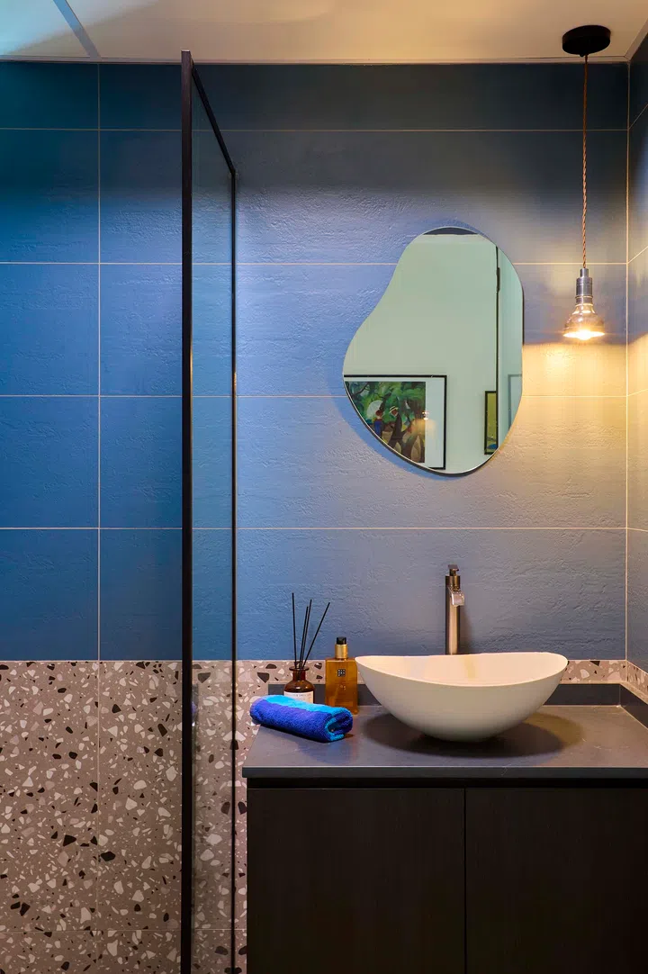 An eclectic bathroom filled with colourful tiles and playful design choices, far from the original industrial theme the couple intended.
