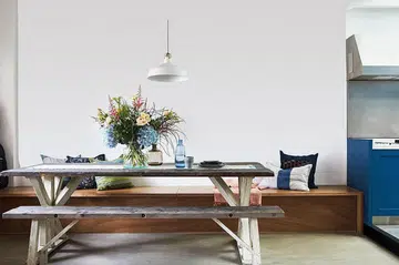 Wood dining bench at a wood dining table, with a built-in storage bench against the wall. Interior design by PIU Design