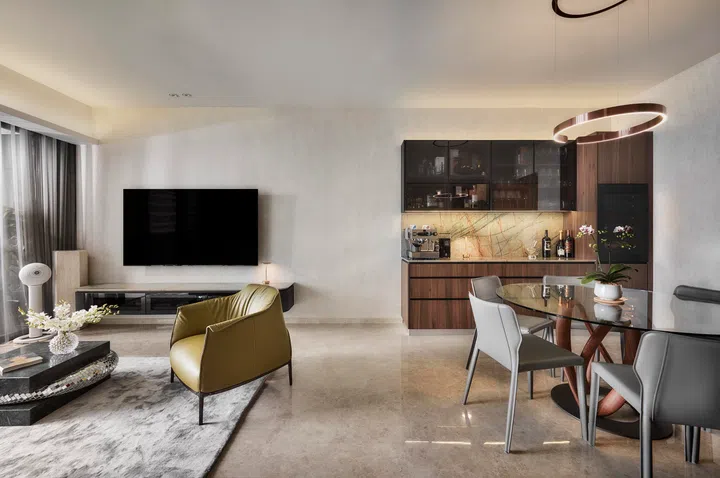 A continuous sequence unites the living, dining and bar areas, where travertine tones, walnut cabinetry and subtly layered lighting form a warm, cohesive backdrop for daily life.