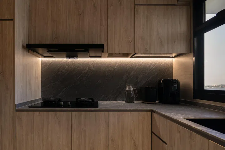 Under-cabinet lighting highlights the veining of the stone backsplash, giving the space a calm, refined glow.