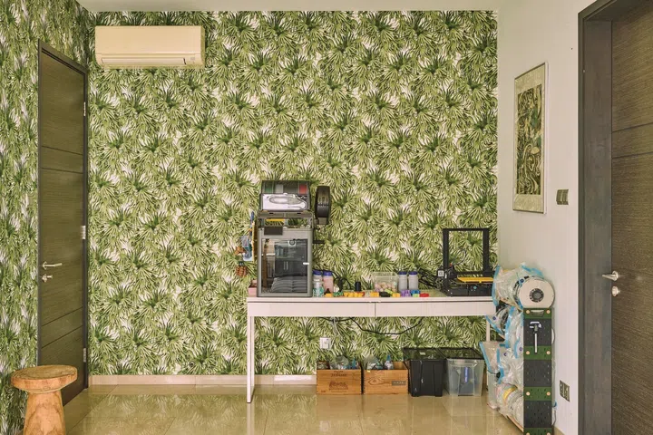 The guest room is decked in a green, tropical wallpaper.