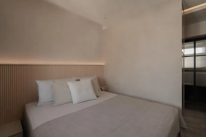 A fluted timber headboard with concealed lighting wraps the bed in a soft, even glow, setting a calm and restful tone in the master bedroom.