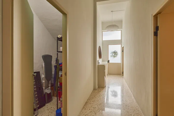 A hidden storeroom is integrated along the corridor, consolidating storage and preserving a single, uninterrupted path through the home.