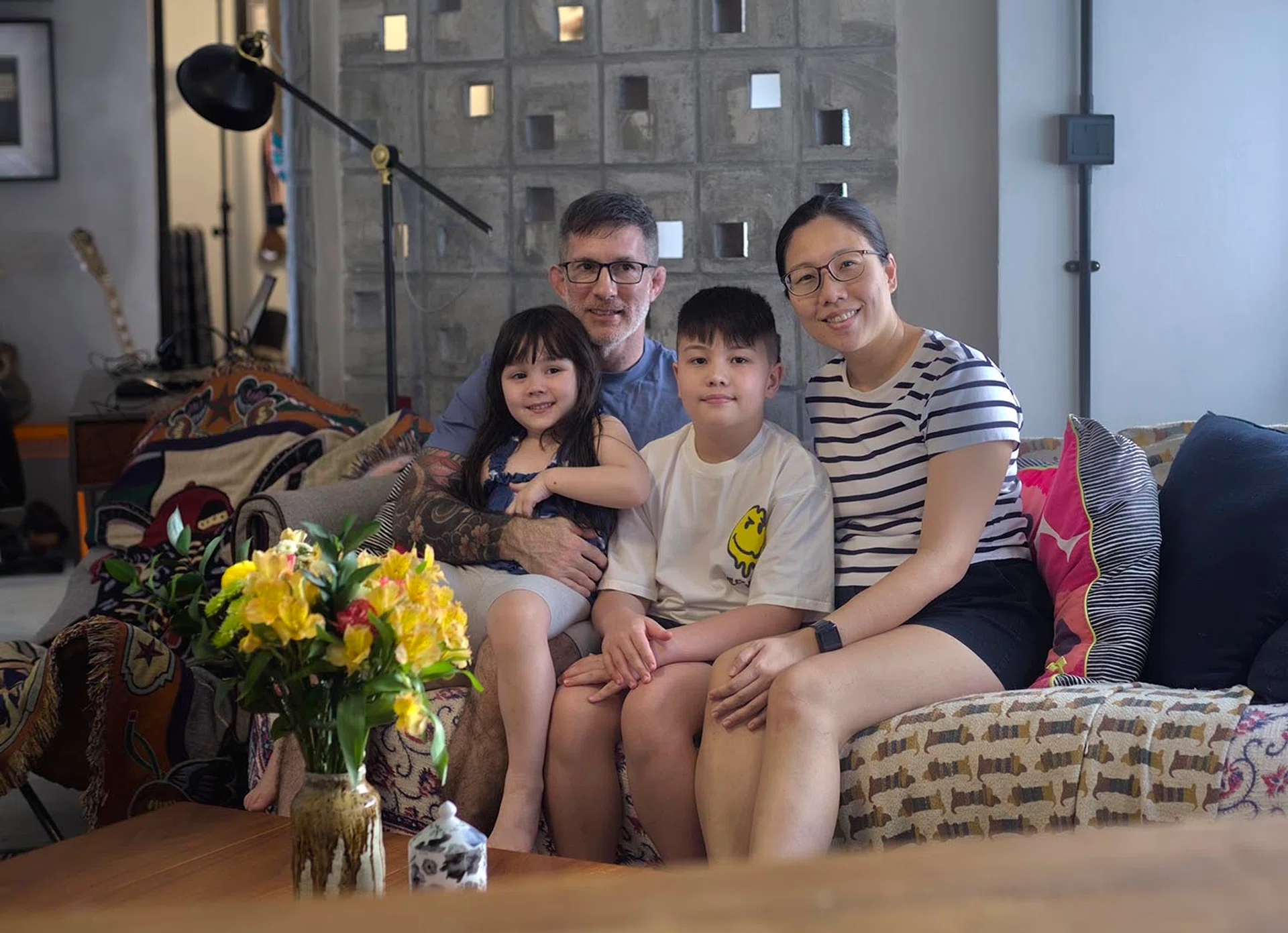 A family portrait of Mike, Grace and their two kids in the living room. 
