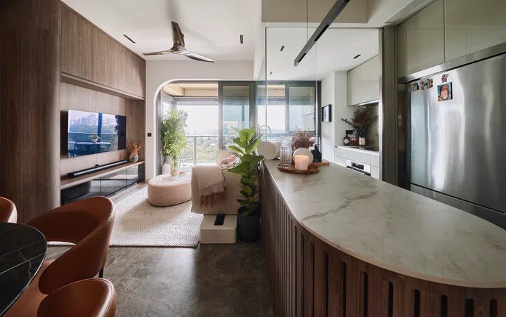 A curved kitchen island wrapped in dark wood and topped with stone, serving both function and elegance in this social, open-concept layout.