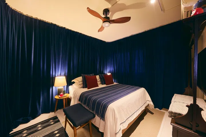 Thick navy stage curtains wrap the bedroom, creating Hermsie’s favourite retreat after long days of hosting.