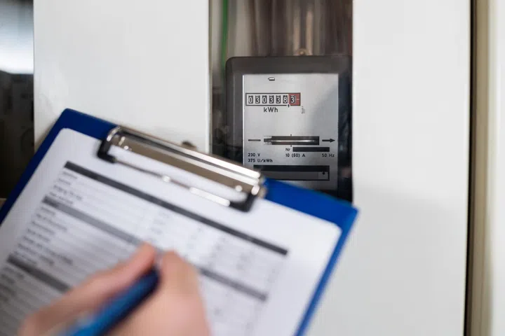 Close-up Of A Technician Hand Writing Reading Of Meter On Clipboard