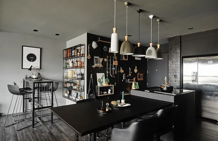 The dining area with a dining table, high dining table, and an all-black wood pegboard to hold kitchen accessories.