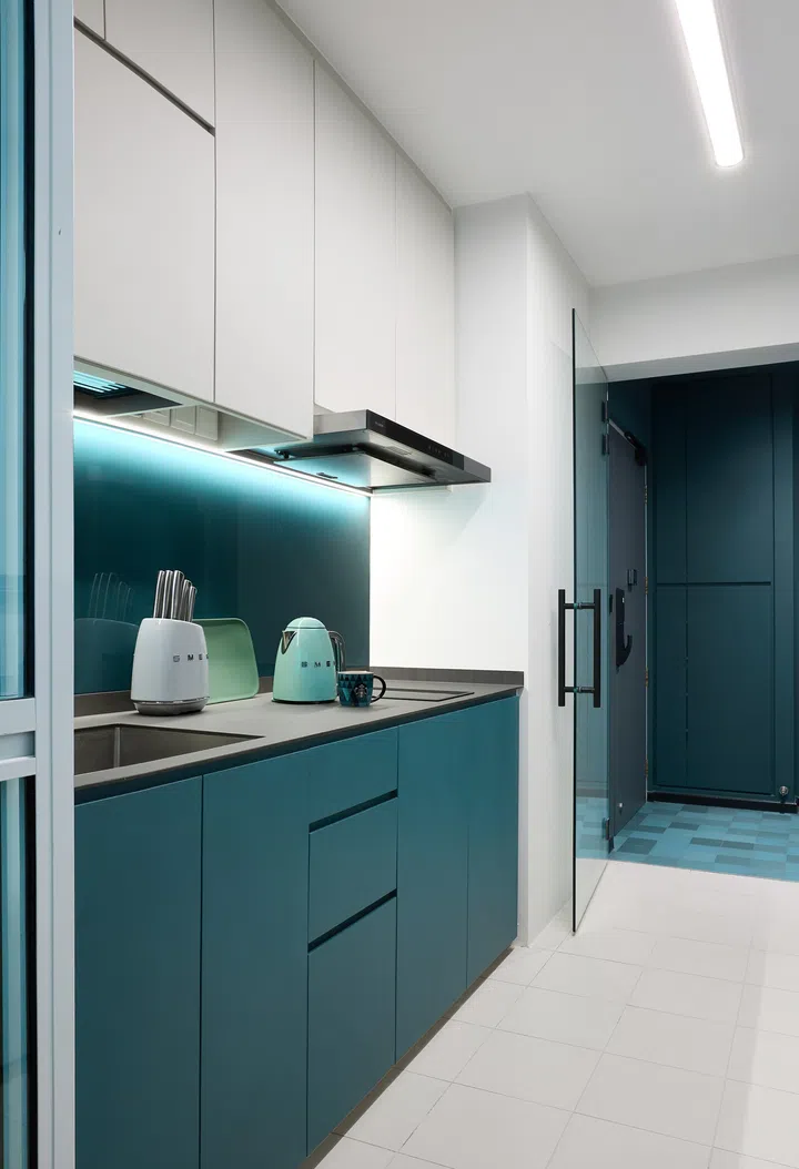 A clean galley-style kitchen featuring green and grey cabinetry, with coordinated countertops and backsplash.