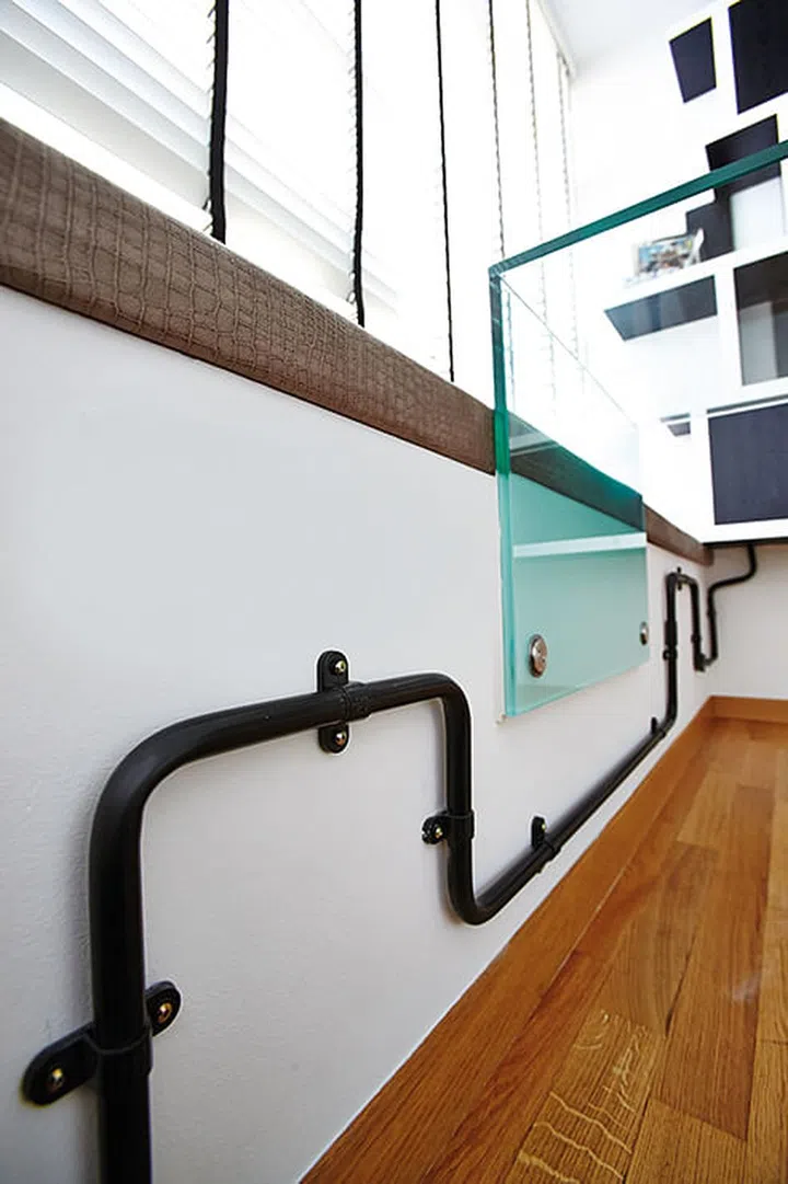 The installation of fibre optic cables threw a spanner in the works, but interior designer, Kelvin, turned the potential eyesore into a design feature by encasing them in black pipes that snake their way through the room.