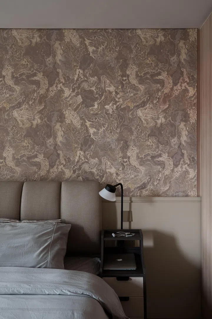 A textured wallcovering adds visual depth behind the bed while keeping within the home’s restrained palette.