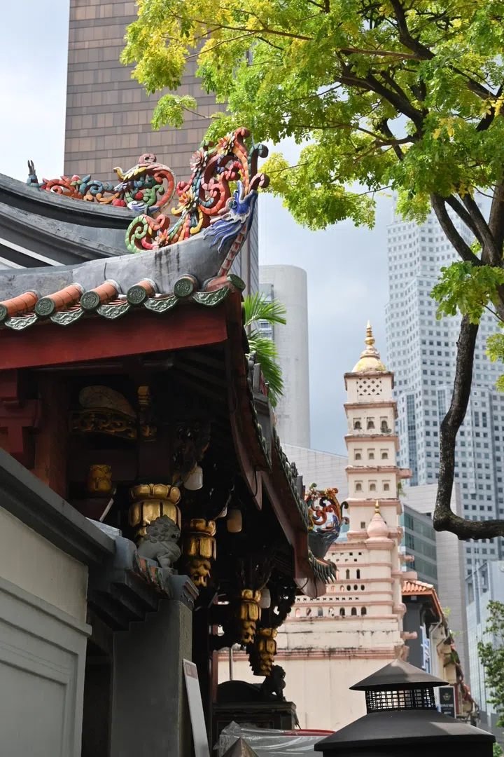 A rich tapestry of cultural temples and architectural forms defines the landscape, set against a backdrop of skyscrapers.