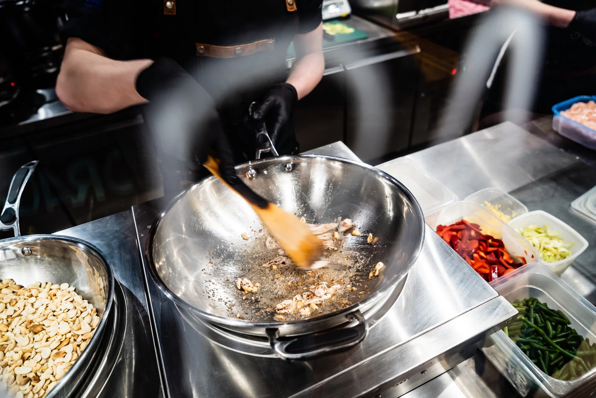 In the heart of a bustling kitchen, a chef expertly stirs sizzling ingredients in a wok.
