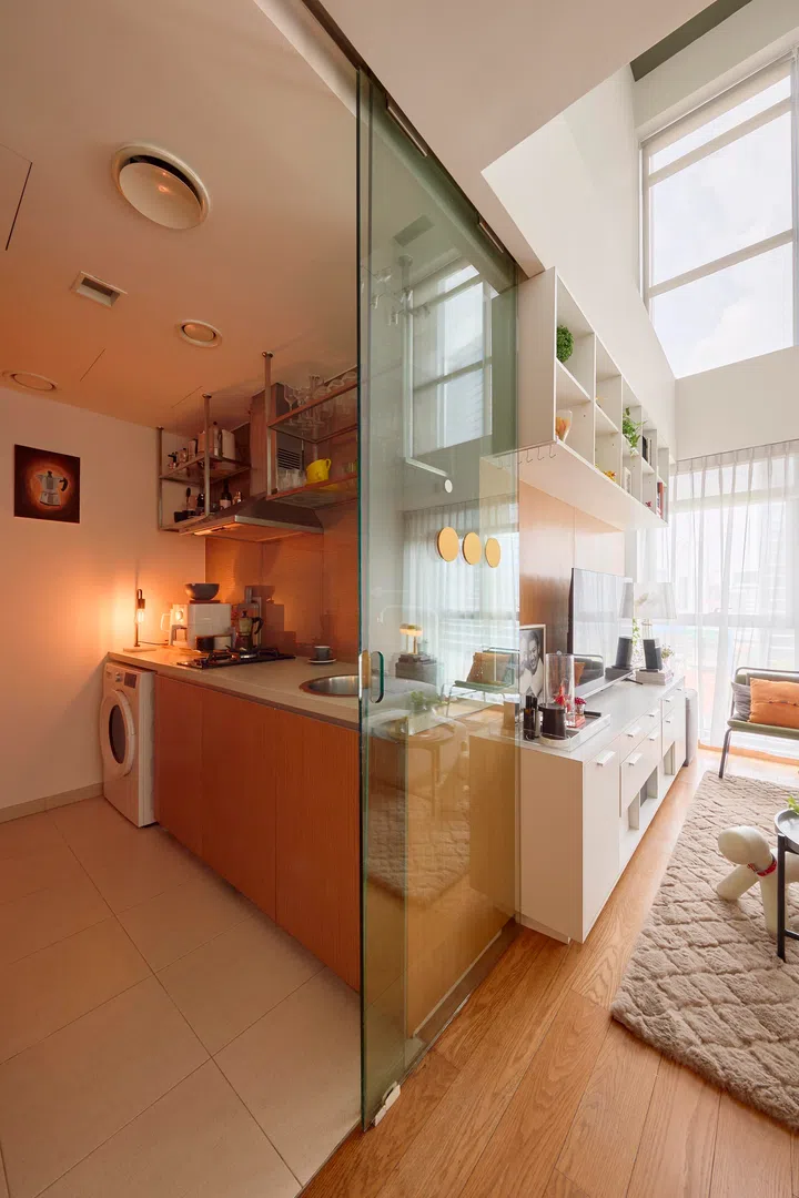 A sliding glass partition separates the kitchen from the living area, maintaining openness while containing the workspace.