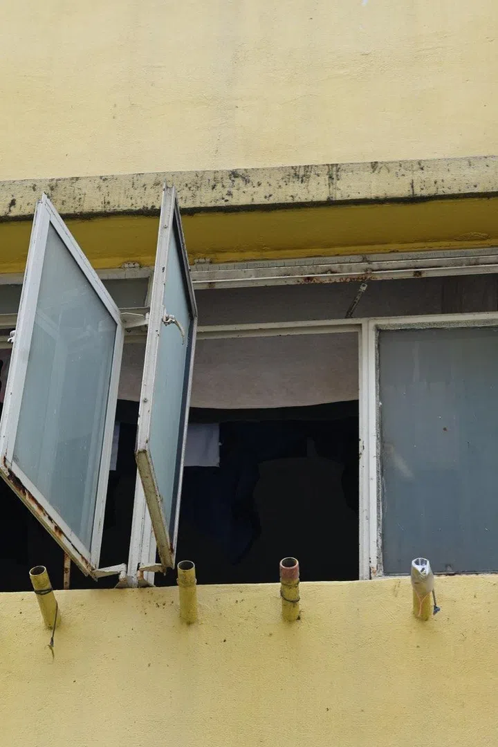 Open windows in a HDB rental flat at Spooner Road with old school open laundry bamboo pole holders and casement windows. Isabel Lim