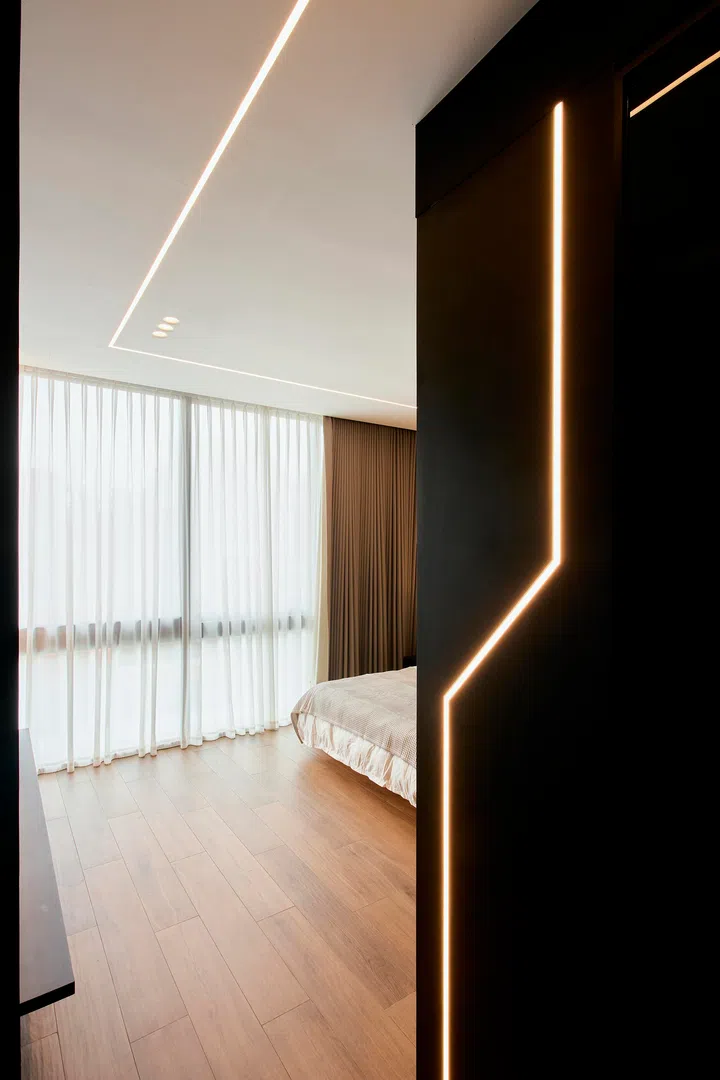 A linear-lit partition marks the transition into the master bedroom, creating a subtle threshold from the corridor.