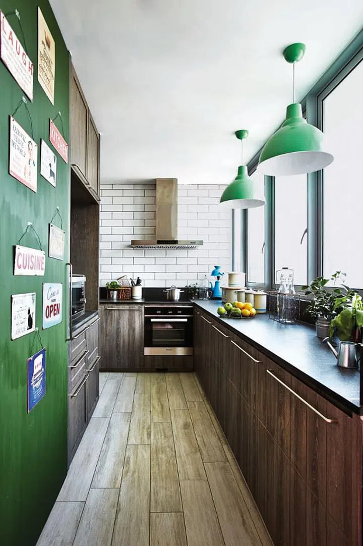 Deep, warm wood tones give the kitchen mood, while fresh green hues pop from its muted canvas. Interior design by Museum Homes.