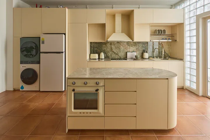 The kitchen is organised around a central island, with full-height cabinetry and a restrained palette creating a calm, cohesive backdrop.