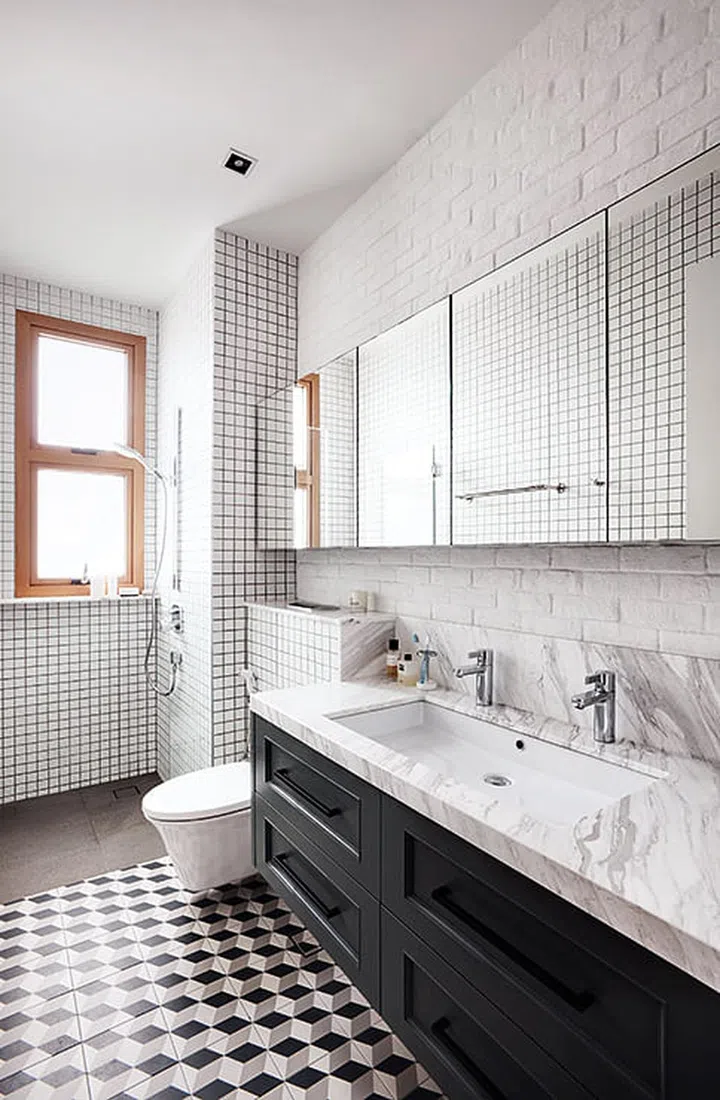 The homeowner's eclectic taste is exemplified in his bathroom, which has a marble countertop, graphic tiled floor and a brick wall.