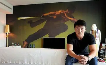Vincent Ng in front of a wallpaper of himself in his living room. He describes the style of his home as minimalist, modern and relaxed. Photo: The New Paper