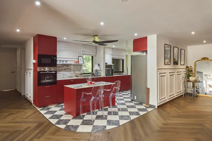The kitchen introduces a bold burgundy palette, with a central island that doubles as the family’s everyday dining area.