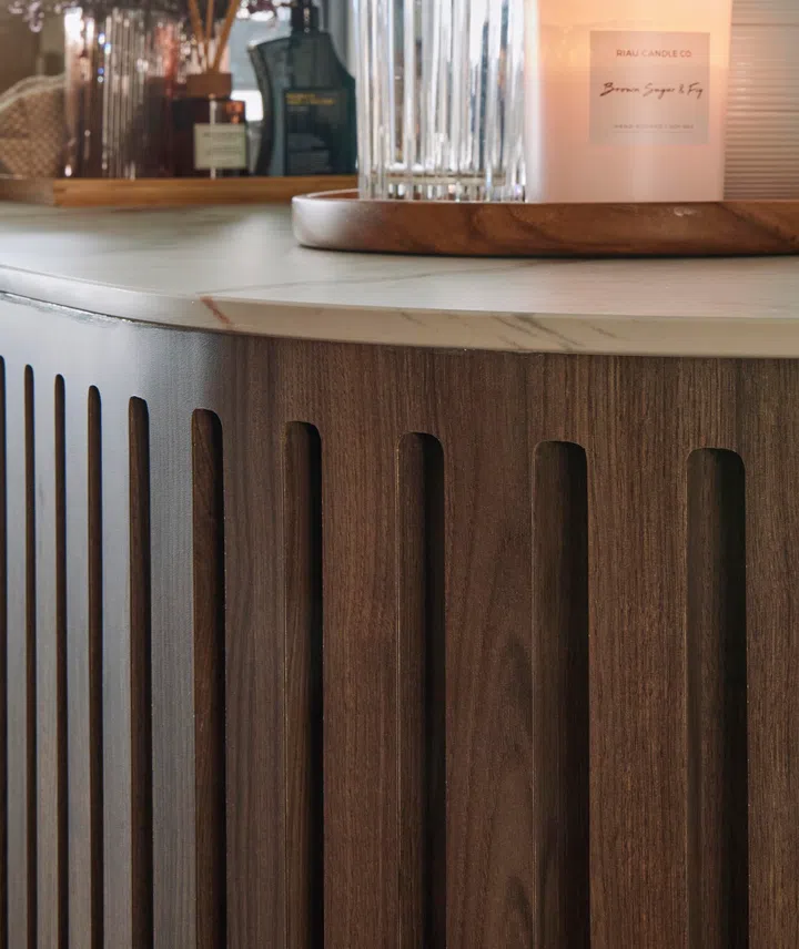 Vertical fluting in rich wood grain adds texture and warmth beneath the luxe marble countertop, subtly elevating the heart of the kitchen.